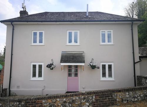 a white house with a pink door at Staggs Cottage in Andover