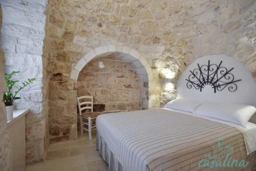 a bedroom with a bed in a stone wall at Trulli Casalina in Cisternino