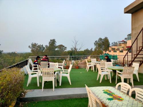 a patio with white chairs and tables on a roof at Hotel Rashmi in Agra