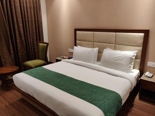 a bedroom with a large bed and a chair at Maple Grand in Agra