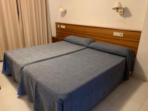 two beds in a hotel room with blue sheets at Apartamentos Marina in Port de Pollensa