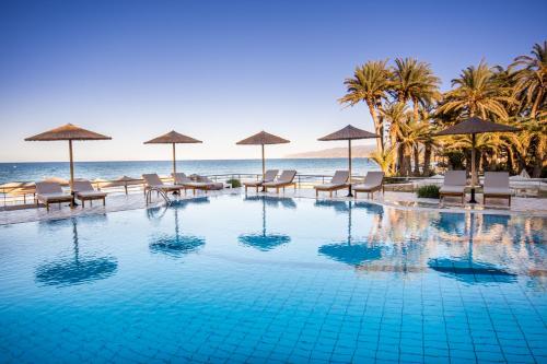 een zwembad op het strand met stoelen en parasols bij Alai Beach Resort in Stalida