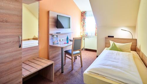 a bedroom with a bed and a desk with a television at Hotel Merian Rothenburg in Rothenburg ob der Tauber