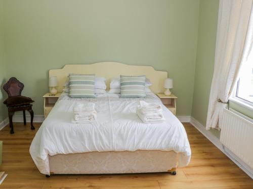 a bedroom with a bed with white sheets and pillows at Kate's Cottage in Ballina