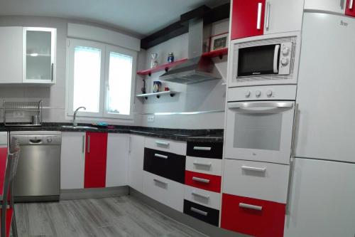 a kitchen with red and white cabinets and a microwave at Despertar en León, al lado de la Catedral in León