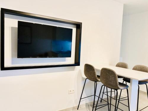 a white table with chairs and a tv on a wall at Canaryislandshost l Brisa del Atlántico in Playa Honda