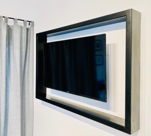 a flat screen tv on a wall with a curtain at Canaryislandshost l Brisa del Atlántico in Playa Honda