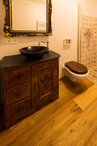 a bathroom with a sink and a toilet with a mirror at Das Kitz - deLuxe ChaletApartments in Jochberg