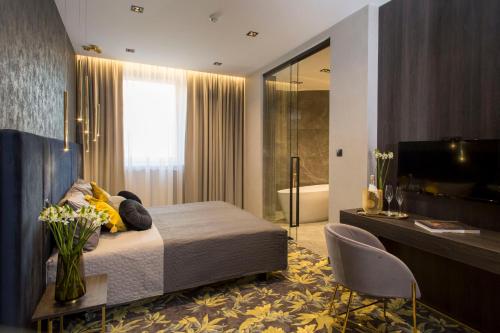 a bedroom with a bed and a tv and a bathroom at Hotel Atrium in Kraków