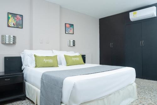 1 dormitorio con 1 cama blanca grande con almohadas verdes en Ayenda 1313 Barahona 72, en Barranquilla