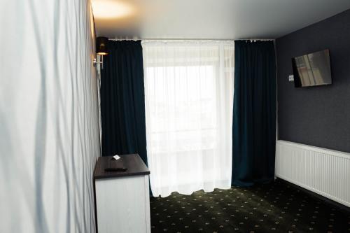 a room with a window with curtains and a desk at River Park hotel in Kovelʼ