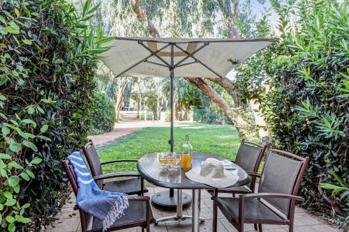 - une table et des chaises avec un parasol sur la terrasse dans l'établissement Résidence Pierre & Vacances le Hameau de la Pinède, à Hyères