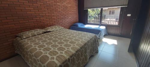 1 dormitorio con cama y pared de ladrillo en Roloff Praça das Rosas, en Gramado