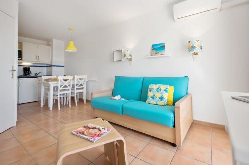 a living room with a blue couch and a table at Résidence Pierre & Vacances Les Rivages Du Parc in Menton