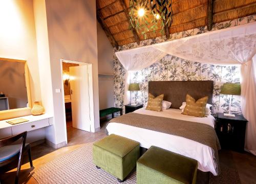 a bedroom with a bed and a desk and a television at Shearwater's Explorers Village in Victoria Falls