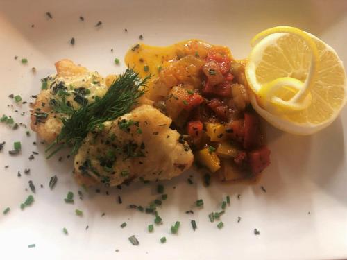 a plate of food with meat and a lemon at Hotel Châlet Du Lac in Iseltwald