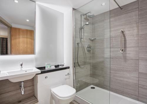 ein Bad mit einer Dusche, einem WC und einem Waschbecken in der Unterkunft Holiday Inn Belfast, an IHG Hotel in Belfast