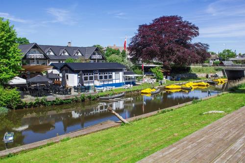 a river with boats in the water next to buildings at Riverside Voerså in Sæby
