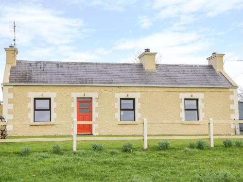 a large yellow house with a red door at Glor Cottage in Ballyhaunis