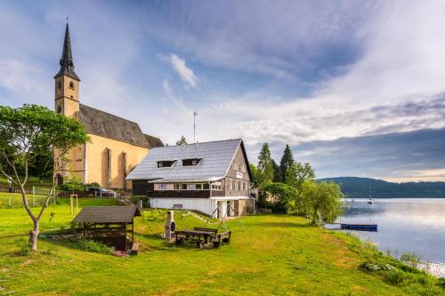 a church sitting next to a body of water at Marvelous lake view apartments - Jezerka Lipno in Přední Výtoň