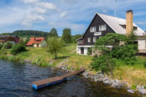 a barge on a river in front of a house at Marvelous lake view apartments - Jezerka Lipno in Přední Výtoň