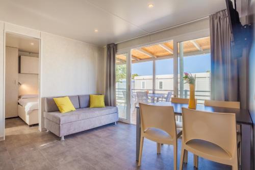 a living room and dining room with a couch and a table at Mobile homes Lussmarin in Mali Lošinj