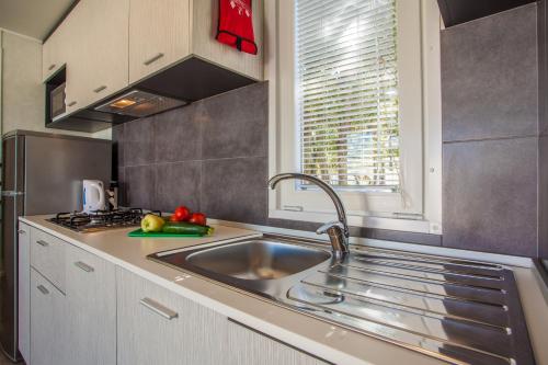 cocina con fregadero de acero inoxidable y ventana en Mobile homes Lussmarin, en Mali Lošinj