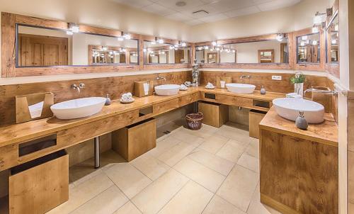 a large bathroom with three sinks and mirrors at Hotel Wirt z´ Engelsberg in Engelsberg