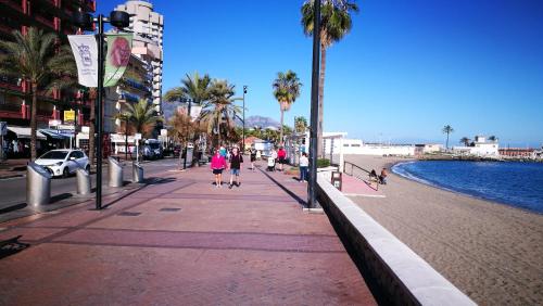 a group of people walking down a sidewalk next to a beach at Apartamento Cervantes in Fuengirola