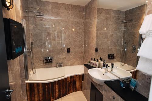 
a bathroom with a tub, sink, and mirror at BrewDog Kennels - Aberdeen in Aberdeen
