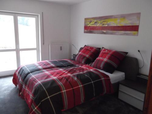 a bedroom with a red and black bed with pillows at FEWO 3 am Sternpoint in Bodenmais