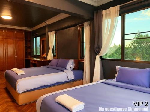 two beds in a bedroom with a window at Ma Guesthouse Chiang Mai in Chiang Mai