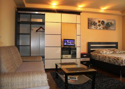 a living room with a couch a bed and a tv at City center Deluxe apartment in Bucharest