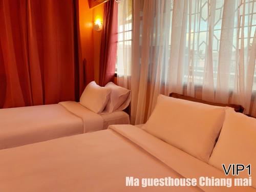 a hotel room with two beds and a window at Ma Guesthouse Chiang Mai in Chiang Mai
