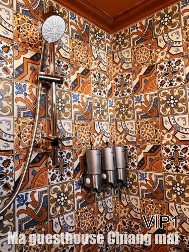 a tile wall with a chandelier hanging from it at Ma Guesthouse Chiang Mai in Chiang Mai