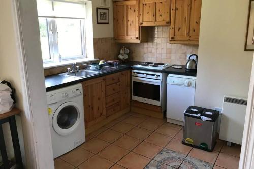 a kitchen with a sink and a washing machine at Sunny Bungalow in Courtown