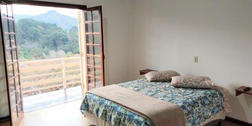 ein Schlafzimmer mit einem Bett und einem großen Fenster in der Unterkunft Vista Bela in Campos do Jordão
