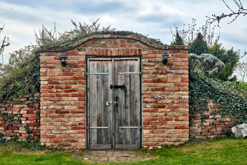 a brick shed with a wooden door in a brick wall at Penzion Na Lednické in Hlohovec