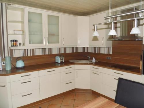 een keuken met witte kasten en een wastafel bij Ferienhaus Heideblüte in Schneverdingen