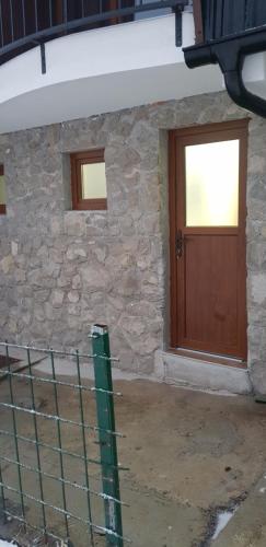 uma casa de pedra com uma porta de madeira e uma cerca em Apartman za dvoje em Travnik