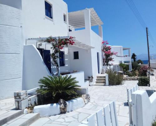 a white house with a fence in front of it at Nicos Studios & Apartments in Logaras