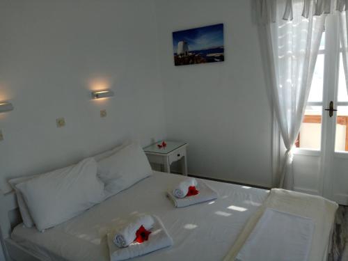 a bedroom with a white bed and a window at Nicos Studios & Apartments in Logaras