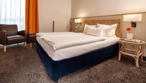 a hotel room with a large bed and a chair at Parkhotel Weiskirchen in Weiskirchen