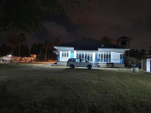 a white car parked in front of a house at night at ALA Beach Lodge - Ketapang Homestay in Kota Bharu