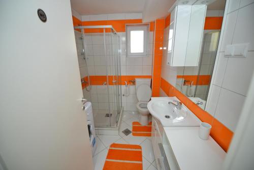 an orange and white bathroom with a sink and a toilet at Apartment Mirela in Sarajevo