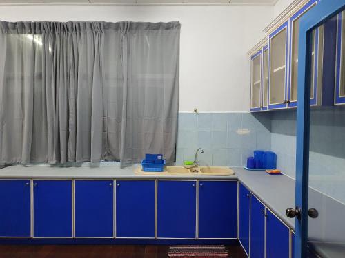 eine Küche mit blauen Schränken und einem Waschbecken in der Unterkunft ALA Beach Lodge - Ketapang Homestay in Kota Bharu