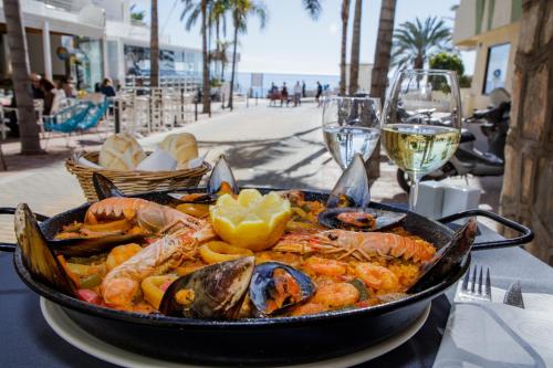 una sartén de mariscos en una mesa con copas de vino en Puerto Azul Marbella, en Marbella