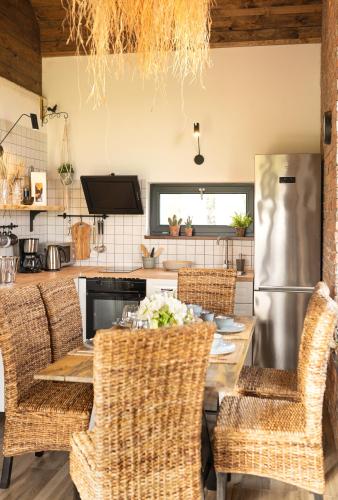 a kitchen with a table and wicker chairs at Pod Mazurskim Niebem boho in Piecki