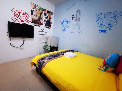a bedroom with a yellow bed and some drawings on the wall at Nandian Homestay in Eluan
