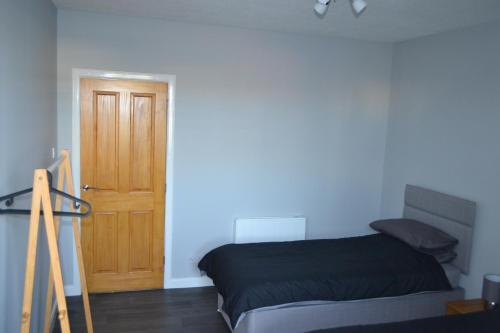 een slaapkamer met een bed en een houten deur bij Harbour View Apartment Wick in Wick
